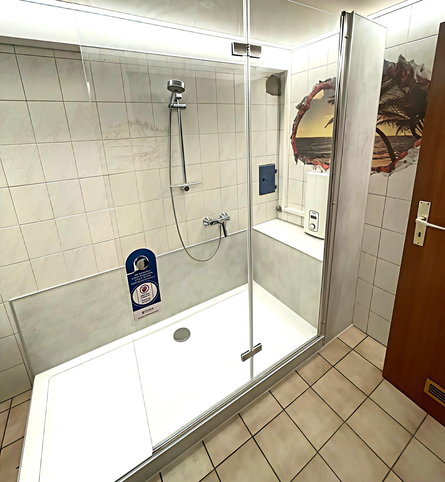 Barrierearme Dusche mit großer Glasabtrennung, integrierter Sitzfläche, Handbrause und Wandmotiv mit Strand- und Palmenmotiv, kombiniert mit hellen Wandfliesen.