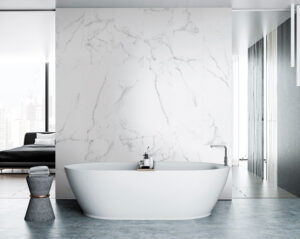 Moderne, freistehende Badewanne vor einer eleganten weißen Marmorwand in einem hellen Badezimmer.