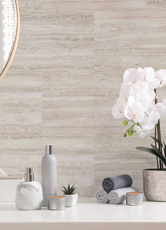 Modernes Badezimmer mit heller Wandverkleidung in Natursteinoptik, dekoriert mit weißen Orchideen und minimalistischen Accessoires.