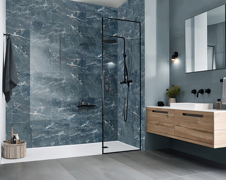 Barrierearme Walk-In Dusche mit Glasabtrennung, blauer Marmoroptik-Wandverkleidung, schwarzer Regenduscharmatur und modernem Waschtisch in Holzoptik.