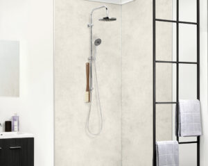 Barrierefreie Dusche mit heller Wandverkleidung in Betonoptik, Glasabtrennung und moderner Regendusche von Novadusch.