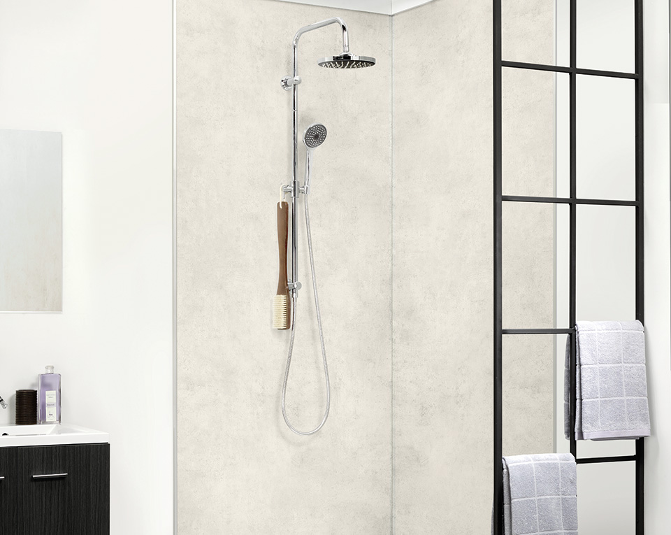 Barrierefreie Dusche mit heller Wandverkleidung in Betonoptik, Glasabtrennung und moderner Regendusche von Novadusch.