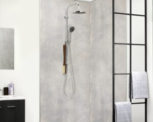 Offene, barrierearme Dusche mit grauer Wandverkleidung in Betonoptik, Regenduschkopf, Handbrause und schwarzer Metall-Glasabtrennung mit Handtuchhaltern.